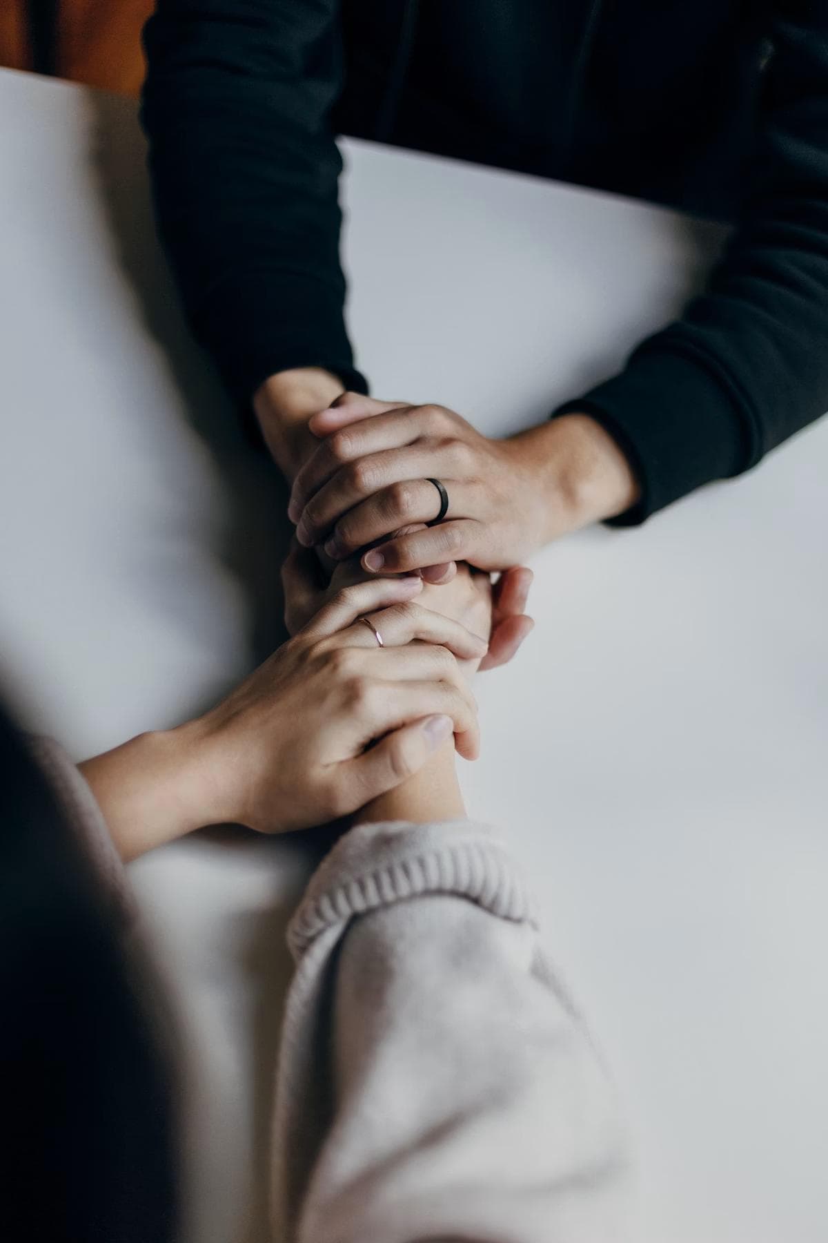 Two people holding hands in support across a table